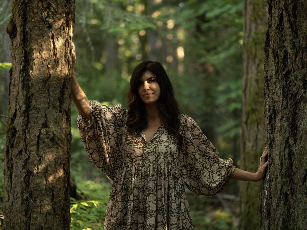 Brandy Nielson standing among tall evergreen trees in a Vancouver Island forest